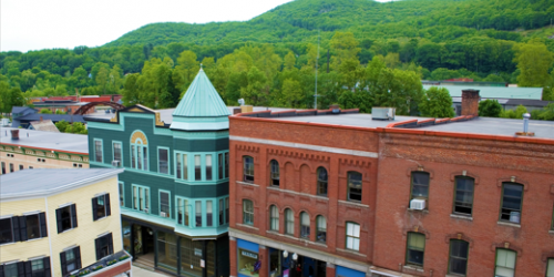 Ariel view of a Vermont downtown - a busy street is lined with brick storefronts. bio