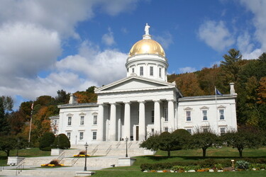 The Vermont Capital Building with a large golden dome in early fall. 