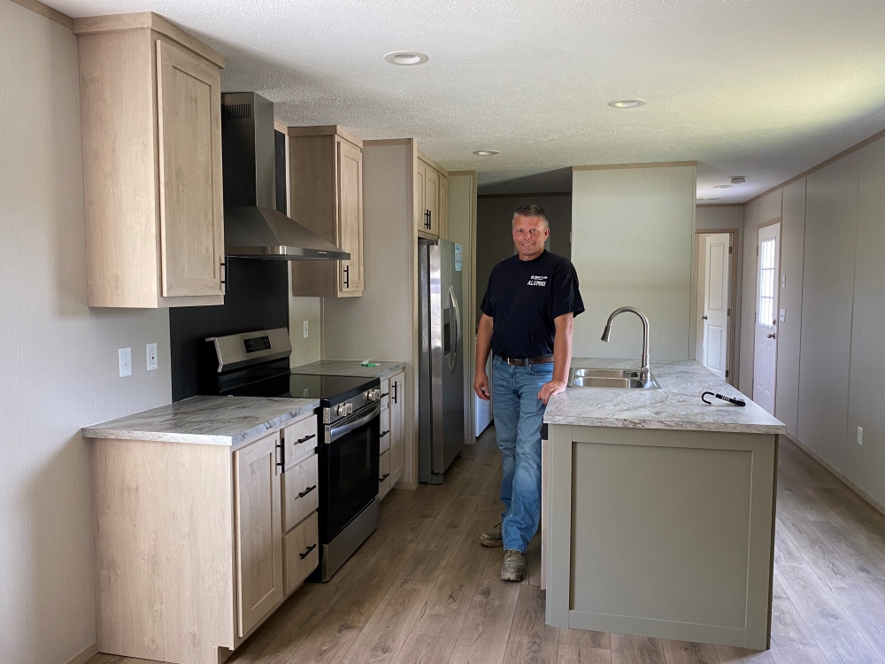 Lawson standing in kitchen of mobile home