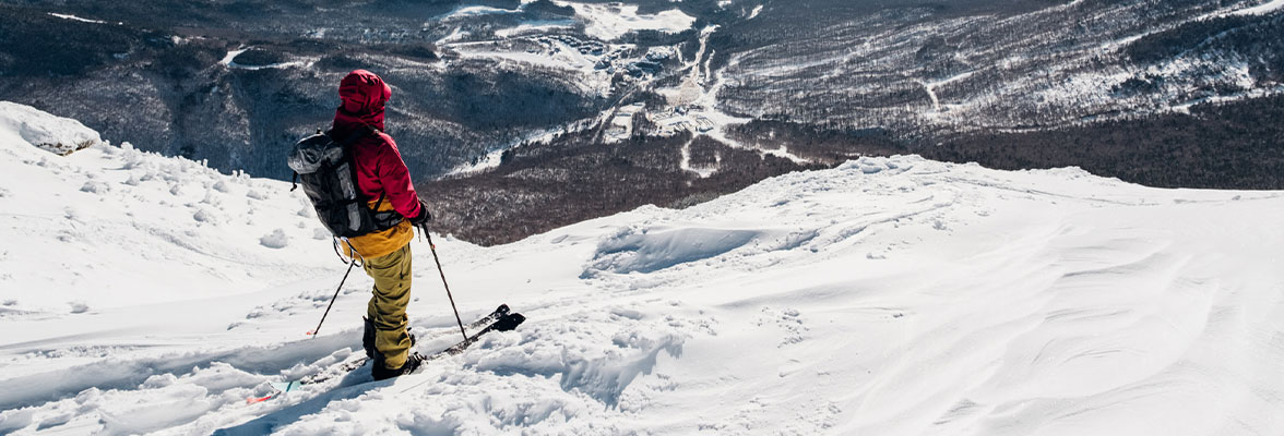 Man standing on stowe mountain in skis looking down