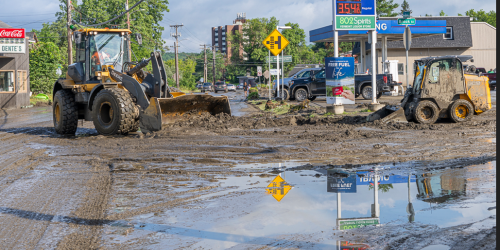 Construction equipment on a road in front of a gas station.