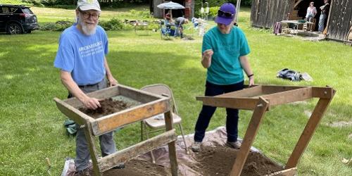 Two people screening soil