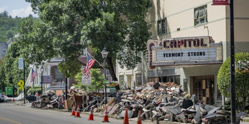 Flood debris piled on the side of the street in front of a movie theatre. 